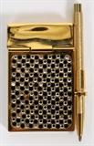 Lot#1175, JUDITH LEIBER CRYSTAL NOTEPAD WITH PEN, L 2 1/4"A gilt metal hinged cover with black and clear crystals set on both sides, with ball point pen.  Stamped: Judith Leiber, New York.  Made in Italy.