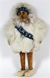 Lot#1303, NATIVE AMERICAN INDIAN FUR & HIDE 'ALASKA' DOLL, H 10 1/2"Having a stuffed linen body with hide mitts and legs, dressed in a fur parka with wool sash reading "Alaska" in beads, also beaded facial features.