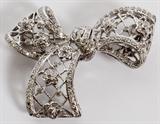 Lot#2065, 1.00CT DIAMOND & 18KT GOLD LADY'S BOW PIN, W 1 1/8" L 1 3/4"18kt white gold lady's bow form pin, featuring 1.00 carat of round diamonds throughout, measuring L. 1 3/4" x 1 1/8", having a total approximate weight of 9.1 grams.