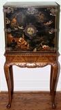 Lot#2213, CHINOISERIE CABINET ON STAND, C. 1900, H 52" W 26"Black lacquer cabinet, fitted with two drawers, and decorated in a landscape scene with figures. Raised on a carved cabriole leg stand. Measuring H. 52" overall, x 26". Circa 1900.