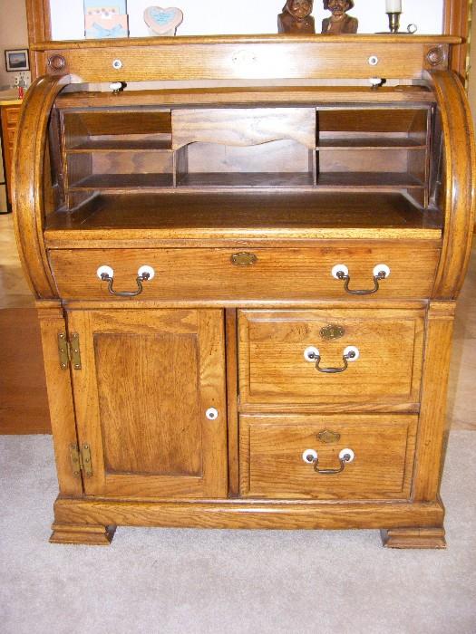 Beautiful Golden Oak replica of antique (1700's) roll-top desk with porcelain detail on brass handle pulls.  Desk is smaller than most roll-tops and measures 34"w X 21.5"d  (w/writing board pulled out: 31") X42"h.  $350.00