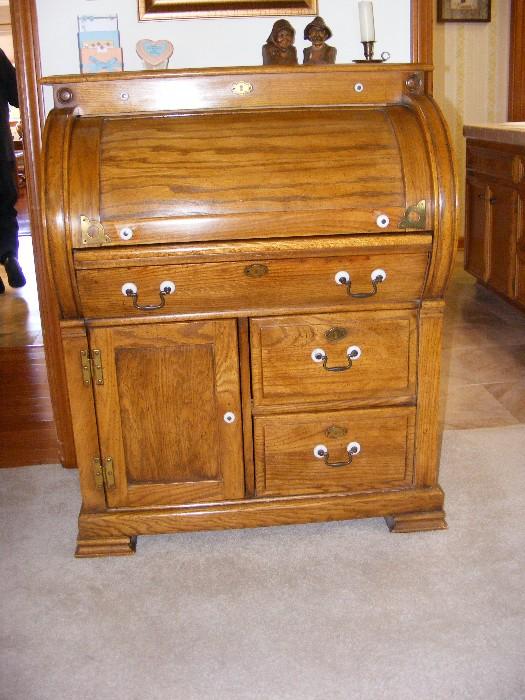 Beautiful Golden Oak replica of antique (1700's) roll-top desk with porcelain detail on brass handle pulls.  Desk is smaller than most roll-tops and measures 34"w X 21.5"d  (w/writing board pulled out: 31") X42"h.  $350.00