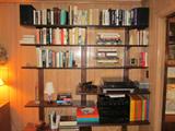 This shelving unit, though attached to the wall, is for sale. It has adjustable shelf brackets for different configurations.