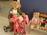 Vintage designer large, medium and small bears with accessories. "Eugene" is featured on his bicycle while "Gabby" and "Spanky" sit nearby.