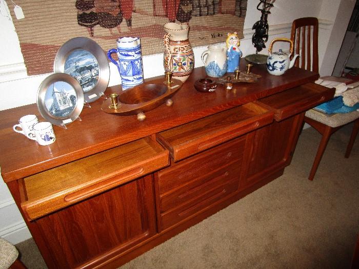 Light wood buffet. Appears to be teak.  Has 7 shallow drawers for place mats/candles/serving pieces.  Storage on each side of shallow pull out drawers.