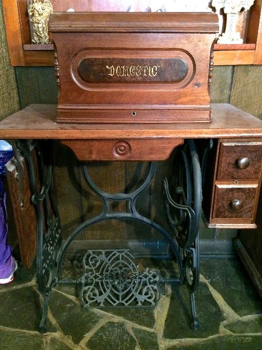 This gorgeous antique Domestic sewing machine features a lift-off cover (machine sits atop the stand, beneath the carved wooden cover)