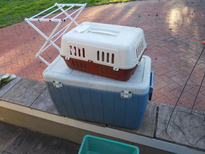 Miniature cat carrier and large blue Cooler.