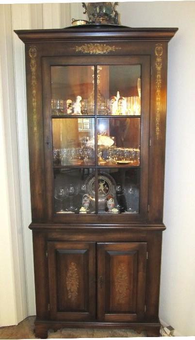Excellent Vintage  Coventry - Kensington Corner Cabinet with rich finish, crafted scalloped  shelves, Lighted display, Key lock security, and elegant gold stenciled / designs  accents.  Cabinet is  lighted and has wood and glass door,  three shelves for display, and double door cabinet storage., and brass pulls  