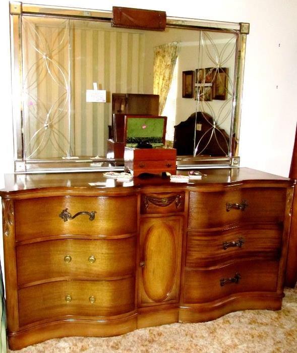 Excellent   Vintage Continental Style Triple Dresser with large Etched Mirror.  Dresser has   rich finish,  beautifully carved center drawer and medallion accents, and a beautiful serpentine / wave front.  Drawers have brass pulls.   This Vintage Triple Dresser and Mirror are   part of Vintage Continental Style Bedroom Set that includes Matching Chest on Chest, Matching Queens Size Headboard, and  Pair of Matching Night Stands (other pieces to this set are shown elsewhere in this collection)
