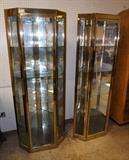 Lot 593:  Pr Gold Tone Decorator Curio Cabinets. Beveled shape. Light up. Interior glass shelves. : Dimensions:  H: 62 inches: W: 28 inches: D: 20 inches --- 