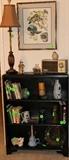 Black bookcase with books and some pottery pieces.