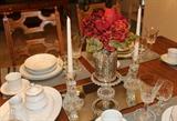 Close-up of china on dining table along with crystal candle holders.