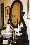 The side view of the antique mahogany dresser with white pitcher and bowl.