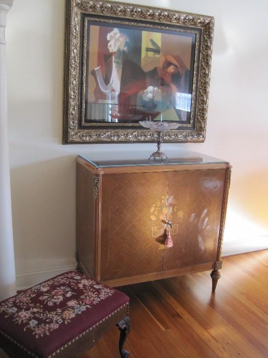 Inlaid French Cupboard with protective glass top. Needlepoint Footstool. Framed art.