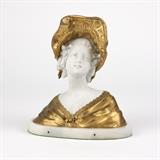 1076  A bisque porcelain and gilt bronze bust of a lady
Late 19th / early 20th century, unsigned, depicting a young woman wearing a bonnet, her dress and hat of gilt bronze, raised on an oval white marble base, 9.75'' H x 8.75'' W x 4.75'' D, est: $800/1200

Provenance: Private Collection, West Hills, CA.  Condition: Overall good condition. Minor rubbed wear and patination to gilt bronze. Areas of minor discoloration to bisque porcelain beneath bonnet; largest area approximately .5'' x .25''. Scattered minor chips and fleabites to edge of marble base; the largest approximately .25''-long. Green felt applied to underside of base.  Your bid indicates acceptance of our Conditions of Sale.  AS-IS.  ALL SALES FINAL