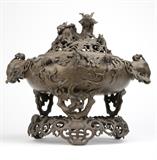 1097  A large Chinese pierced bronze censer
Probably late Qing Dynasty (1644 - 1912), with archaistic seal to underside, the dragon-form finial surmounting a circular pierced scrolling branch-form cover issuing leaves and blossoms and dotted with mice, over a similarly decorated squat circular body flanked by two elephant head handles, supported on three branch-form supports and raised on a pierced scrolling tripod base centering a dragon, 18.5'' H x 20.25'' W x 15.75'' D, est: $800/1200

Provenance: Private Collection, La Jolla, CA.  Condition: Overall good condition. Topmost dragon lacking barbels to each side of mouth. Lacking pin to lower section of one elephant-head handle; handle somewhat loose. General minor marks, scratches and nicks commensurate with age. Scattered areas of darkening to bronze and minor oxidation throughout.  Your bid indicates acceptance of our Conditions of Sale.  AS-IS.  ALL SALES FINAL