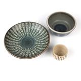 1099  A group of 3 Claremont College stoneware ceramic bowls
Each second half 20th century, Claremont, CA, two bowls by Harrison McIntosh (b. 1914 Claremont, CA), the first: signed with impressed chop ''HM'', the shallow circular body raised on a short circular foot, glazed to exterior in mottled blue, decorated to interior with sunburst stripes radiating from a blue center over a mottled beige and blue-spotted wax resist ground; the second: incised signature ''McIntosh'', with paper label ''Handthrown / Stoneware / Harrison / McIntosh / Claremont / California'', the slightly tapering bulbous body raised on a short circular foot, glazed all-over in speckled beige, with vertical black stripes to exterior; together with a third bowl, signed to underside ''RD'' for Rupert Julian Deese (1924 - 2010 Claremont, CA), the circular body raised on a short circular foot, glazed in mottled greyish blue and dark blue to interior, with blue overlapping stripes to exterior, 3 pieces, the first: 2.25'