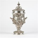 1144  A Bacchic sterling silver lidded urn with handles, after Paul de Lamerie
London, with spurious Paul de Lamerie maker's mark and 1741 date mark, a cast copy after Paul de Lamerie, the twisted acanthus finial-topped domed lid over an urn-form body centered by branch-form handles, over a circular socle on a domed, stepped base, the whole intricately chased and repousse-decorated with flowers, foliage, rocaille, grape vines and clusters, Bacchic putti, lions and heads of Bacchus, 15'' H x 7.5'' W x 6.375'' D, 82.605 oz troy approximately, est: $3000/5000

Provenance: Private Collection, La Jolla, CA.  Condition: Overall good condition. Not monogrammed. General marks, scratches, rubbing and tarnishing commensurate with age. Scattered minor dings and scratches to interior rim of urn mouth, lid and foot; additional minor rubbed wear around outer bottom edge of foot.  Your bid indicates acceptance of our Conditions of Sale.  AS-IS.  ALL SALES FINAL