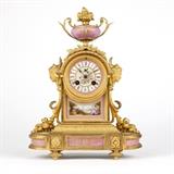 1161  A gilt bronze and Sevres-style porcelain mantel clock, Japy Freres
Late 19th / early 20th century, stamped to movement, case, and original pendulum ''8277'', further impressed to backplate with Japy Freres / Med. D. Honneur pastille, the porcelain panels inscribed ''8277'' and with further illegible notes verso, the circular pink-painted porcelain dial decorated to the central reserve with a bird alighting on flowers, surrounded by black Roman numeral hour markers separated by applied turquoise ''jewels'', within an urn-topped arched rectangular case flanked by espagnolettes issuing floral margents centering a painted plaque depicting figures in a verdant landscape, supported overall on an outset oblong base inset with further porcelain plaques, on toupie feet, 14.5'' H x 10.75'' W x 5'' D, est: $500/700

Provenance: Private Collection, Pasadena, CA.  Condition: Overall good condition. Clock face with break and subsequent repair to porcelain between the VIII and IX hour markers (