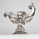 1186  An Austro-Hungarian .800 silver shell-form centerpiece bowl, Bruder Frank
Late 19th century, with Diana standard mark for .800 fineness to body and base, further marked with small ''AV'' import mark within a clipped-corner rectangle and ''BF'' within an oval for maker Bruder Frank, the cherubs each marked with dog's head small article .800 standard mark, the pierced-rim shell-form bowl flanked by winged cherubs clutching plaques each monogrammed ''MR'', over a rocaille and foliage-wrapped stem raised on a pierced rocaille-topped notched oval base, 15.75'' H x 15.5'' W x 10.5'' D, 136.875 oz troy approximately, est: $12,000/18,000

Provenance: Private Collection, La Jolla, CA.  Condition: Overall good condition. General light marks, rubbing, and tarnishing commensurate with age. A .25'' crack and apparent repair to silver near upper terminal of shell and a shallow .5'' x .25'' dent to rear of bowl. An approximately .75''-long loss to one end of garland; a leaf has been bent over t