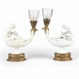 1218  A pair of French biscuit porcelain lamps
Late 19th / early 20th century, each inscribed ''Canova'', the male further inscribed with Sevres-style interlaced double ''L'' mark, modeled after ''L'etude'' and ''La Philosophie'' designed by Simon Louis Boizot (1743 - 1809 French), one depicting a male figure, the other a female, each reading and seated atop oil lamps, mounted with gilt metal sockets and scalloped edge cut glass shades on oval bases, electrified, 2 pieces, the female: 18'' H x 13'' W x 5.25'' D; the male: 18.5'' H x 12.25'' W x 5.25'' D, est: $3000/5000

Provenance: Private Collection, La Jolla, CA.  Condition: Overall good condition. Each with general marks, scratches and rubbing commensurate with age; gilt foliate margents somewhat loose. Shades later replaced. The male figure lacking writing implement to right hand and one screw to secure glass shade; not retained. Same figure with a .25''-long firing crack to hairline. The female with white paint applied to arms, h