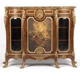 1221  A Regence style gilt bronze-mounted marquetry vitrine cabinet
Mid to late 19th century, faintly stamped ''PS'', possibly for Paul Sormani (1817 - 1887 Paris), to verso of one bronze mount, the beveled-edge serpentine marble top over a gilt bronze haloed Apollo head surmounting a locking cabinet door with hand-painted Vernis Martin panel depicting Venus, the Graces and puttis at Vulcan's forge, enclosing a rosewood-interior cabinet with two adjustable shelves, flanked by two locking glazed cabinet doors each enclosing two shelves, the whole decorated throughout with marquetry, gilt bronze banding and rocaille, raised on short curved legs with paw sabots, with key, 51.25'' H x 67.75'' W x 21'' D, est: $5000/7000

Provenance: Private Collection, Pasadena, CA.  Condition: Overall good condition. With scattered chips and losses to marble top; the largest an approximately 1.25'' x 1'' loss at rear edge. Later replaced back panels to glazed-front cabinets; each panel with a vertical spl