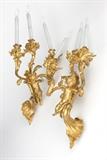 1240  A pair of French gilt bronze three-light wall sconces
Late 19th century, one stamped to verso of mount ''v'', each with three curving foliate-clad arms each supporting an urn-form acanthus-clad socket inset with a faux candle, issuing from a scrolling rocaille support surmounted by a winged putti; one clutching an arrow in each hand, the other with a bow and a single arrow, electrified, 2 pieces, each overall: 33.5'' H x 15'' W x 8'' D, est: $2000/3000

Provenance: Property of a Private Collection, Malibu, CA.  Condition: Overall good condition. General marks, scratches and rubbing to gilding commensurate with age. Re-gilt. Drilled for electricity. Wiring should be checked by a qualified electrician prior to use. Puttis' arrows lacking heads.  Your bid indicates acceptance of our Conditions of Sale.  AS-IS.  ALL SALES FINAL