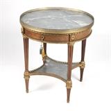 1242  A Louis XVI style lamp table
Late 19th / early 20th century, the circular galleried top inset with gray marble over a single drawer with laurel-wreath pull, supported on four fluted tapering legs connected by a quatrefoil marble-inset under shelf, on bun feet, 29'' H x 26.25'' Dia., est: $500/700

Provenance: Private Collection, Pasadena, CA.  Condition: Overall good condition. General marks and scratches to marble top and under shelf.  Your bid indicates acceptance of our Conditions of Sale.  AS-IS.  ALL SALES FINAL