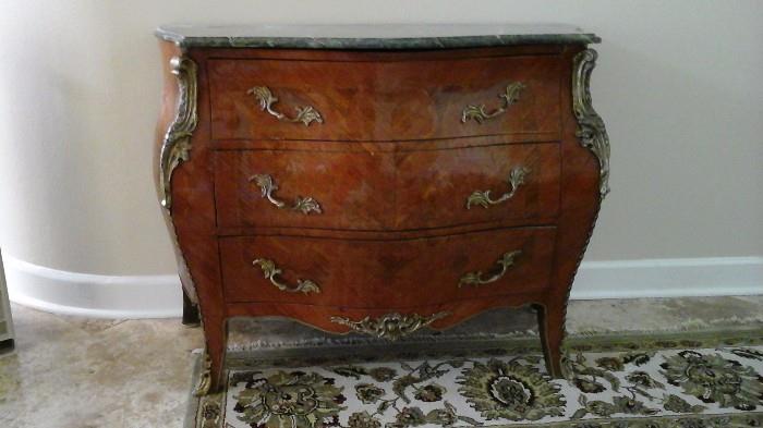 Antique curved front chest with detailed brass trim.