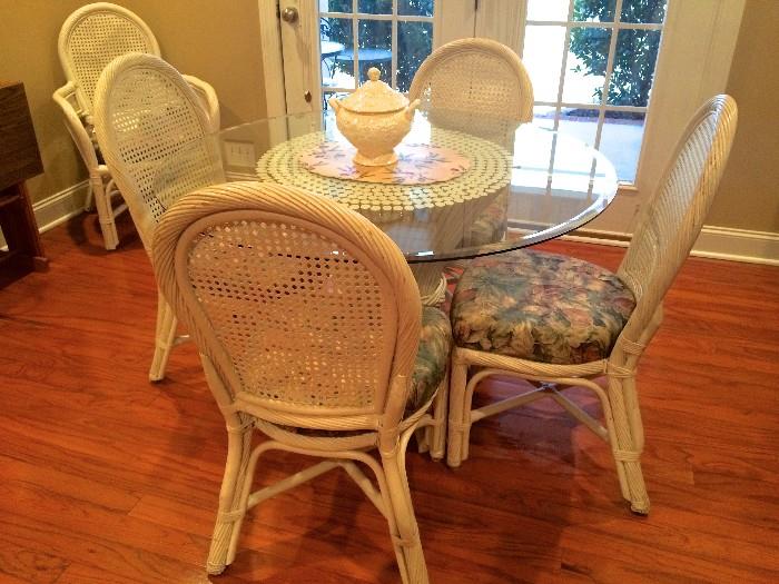 Breakfast room glass-top table with four white wicker chairs and two arm chairs