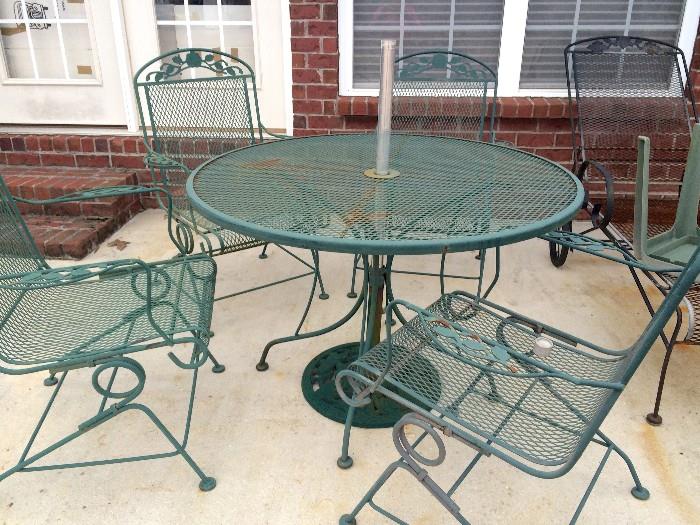 Green wrought-iron table and four chairs, metal umbrella stand, and (not yet shown) matching cushions and umbrella