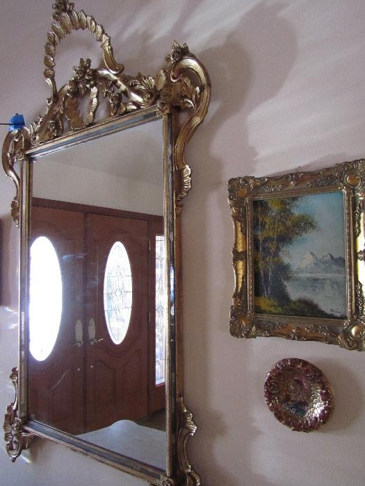 a Transitional style mirror with cresting foliate and floral lead designs flanked by carved scrolls, a small painting, mosaic roman art