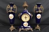 65 - Three piece cobalt blue clock set, signed Royal Bonn, clock - 17 in. T, 9.5 in. W, 5 in. D., urns - 16 in. T, 7 in. W