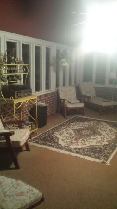 Great sunroom full of furniture, lamps, baker rack and bird cages.