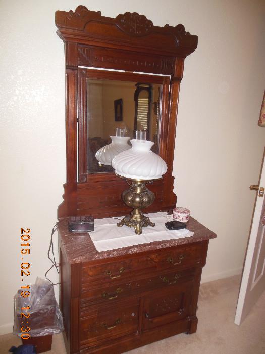 Antique dresser with mirror, 4 drawers and a brown/reddish marble top .  The mirror is heavily carved and the mirror is beveled.  Excellent Condition.