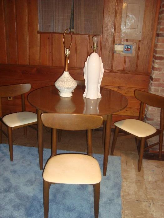 Mid-century round table with four chairs and two mid-century lamps.