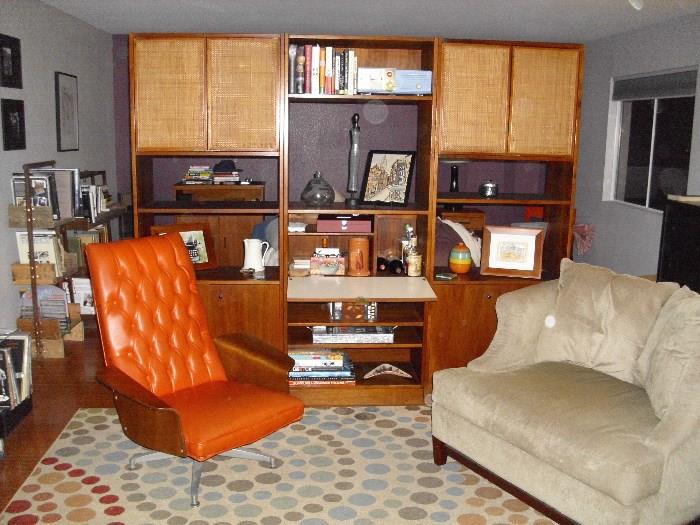 3 piece midcentury modern walnut wall divider, Plycraft chair, pair of chair and a halfs, vintage patterned rug, (in background) repurposed bookshelf made of wood and metal piping