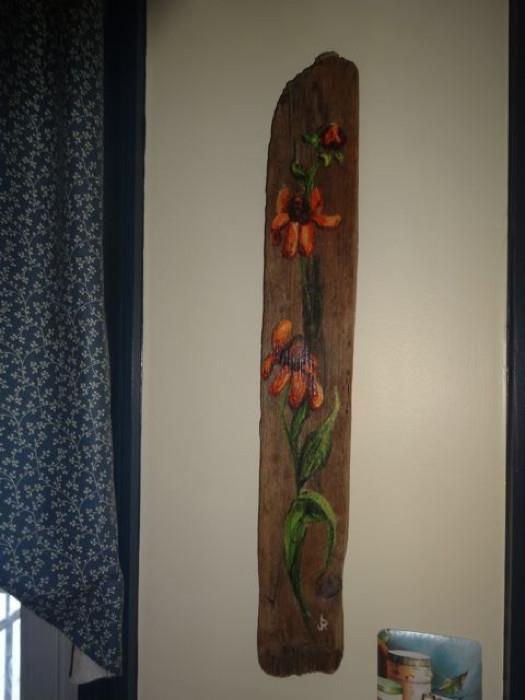 A painted wood plank with a floral design.