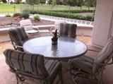 Patio table w/ 2 side chairs and 2 swivel rocker chairs. Cushions are off-white/green/gray.