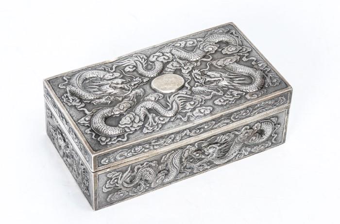 Lot 1021:  LUEN WO SHANGHAI CHINESE EXPORT SILVER BOX: Circa late 19th to early 20th century, hinged lid, repousse dragons in clouds motif on all sides and lid, vermeil interior, marked on base with Chinese export mark and Luen Wo ''LW'' in lozenge. Overall measures 2'' h. x 5 7/8'' x 3 3/8'', approx. 10.6 troy oz.
CONDITION: Spotting to vermeil.