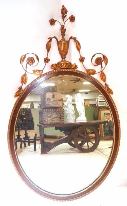 Lot 121:  Antique Regency style Mahogany & Gilt Oval Mirror. Oval Mahogany Frame with Gilt metal & gesso urn & leaf elements. : Dimensions:  H: 45 inches: W: 26.5 inches --- 