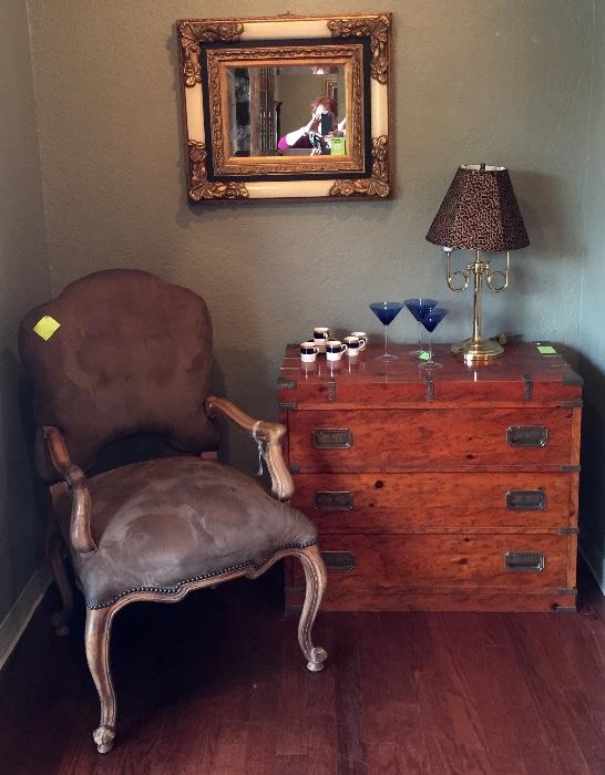 One of two taupe side chairs, mirror, lamp, and campaign chest.