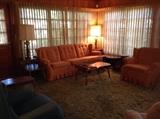 Den furniture includes orange plaid sofa, chair, recliner, colonial hardwood lamp and coffee tables.