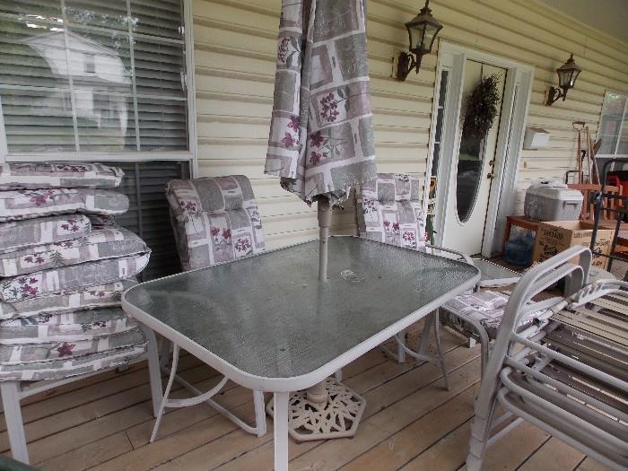 Patio set. 6 chairs, 2 foot stools all with cushions. Glass top table with umbrella and stand. one small side table all to match