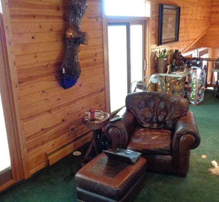 Matching oversized leather chair & ottoman with hand carved wood eagle on wall.