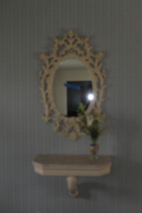 Decorative mirror with stone-topped shelf.