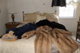 Fur coats and quilt and pillow set. Full-size bed with brass headboard.