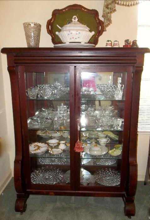 Mahogany Empire China Cabinet with mirrored backs and plate glass shelves.   This piece matches the table and chairs in the breakfast area of the lower den! Top and bottom shelf:  Fostoria "American"; shelf #2: assorted cut crystal; shelf #3: all hand-painted china servers.  Beautiful tureen and large cut crystal vase plus Fitz & Floyd salt and peppers!