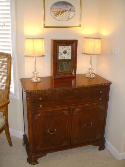 Mahogany chest displaying glass lamps & 19th Century Seth Thomas 30 hr. clock.  Signed artwork above.