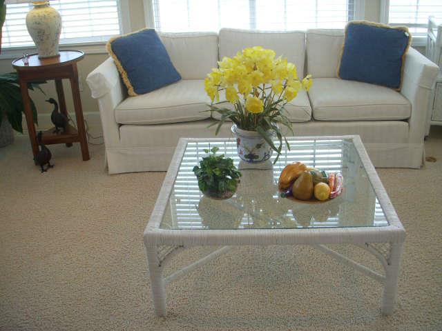 Wicker and glass coffee table.  Sofa is custom white-on-white upholstered piece.  